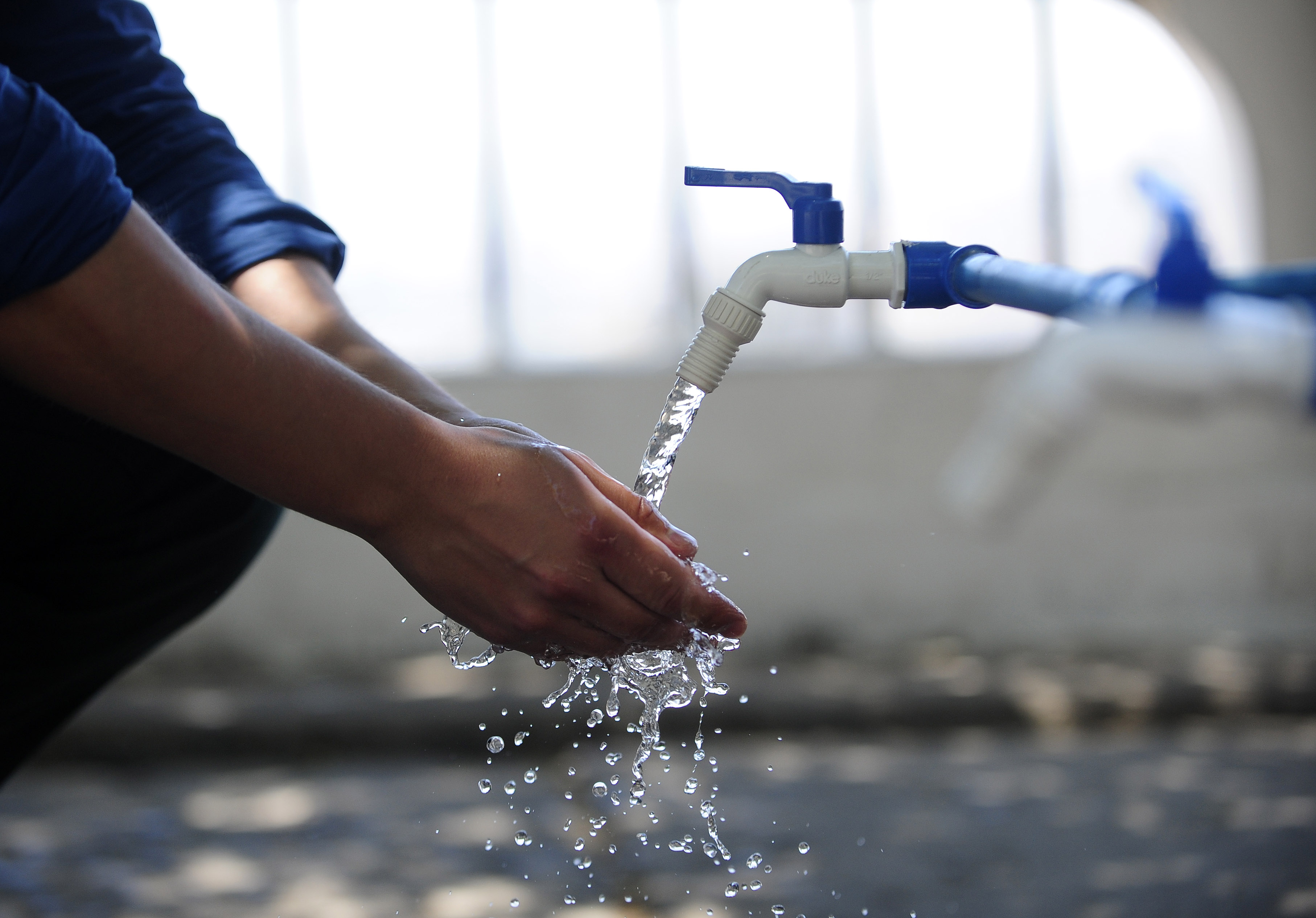 Persona lavándose las manos con agua