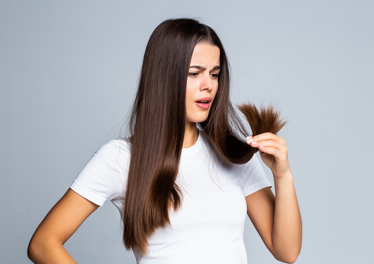 Sad Girl Looking At Her Damaged Hair Isolated On White Background