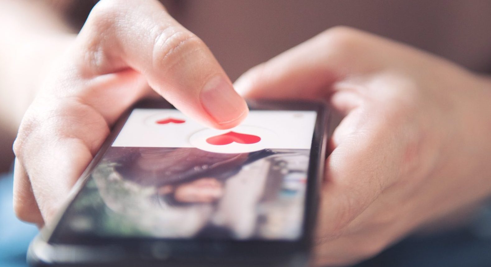 Finger Of Woman Pushing Heart Icon On Screen In Mobile Smartphone Application. Online Dating App, Valentine's Day Concept.