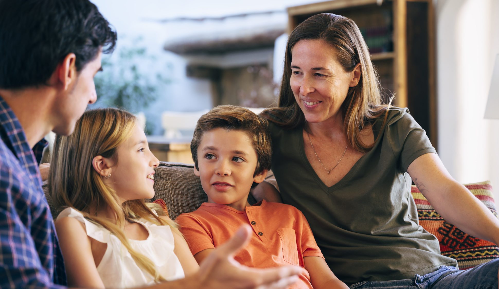 Young Spanish Family Together On Sofa In Family Home