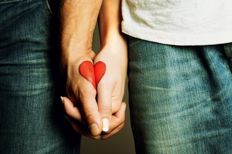 Red Heart Drawing On Hands Of Couple