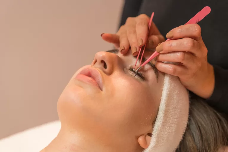 Close Up View Of A Woman During An Eyelash Extension Procedure In A Beauty Salon.