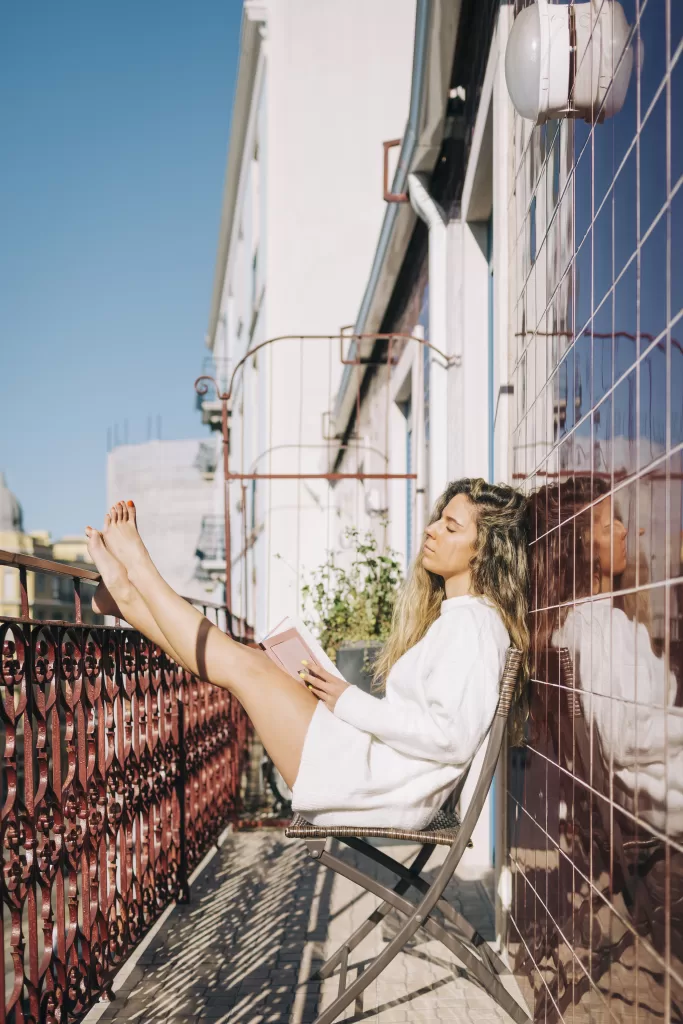 Serene Young Woman Reading Book On Sunny Apartment Balcony, Lisbon, Portugal